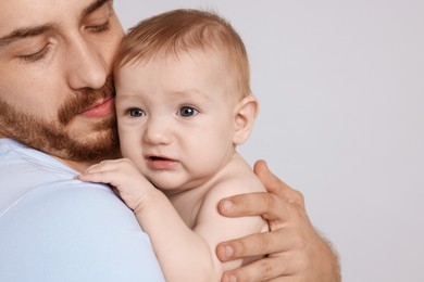 Photo of Father with his cute baby on grey background, closeup