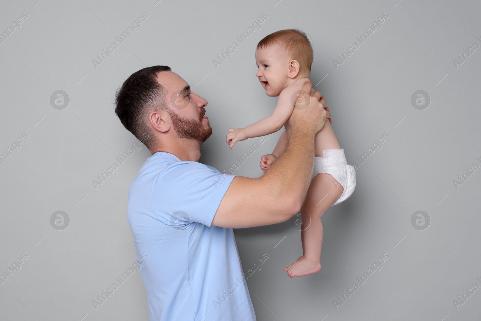 Photo of Father with his cute baby on grey background