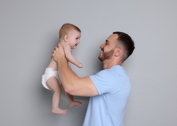 Photo of Father with his cute baby on grey background