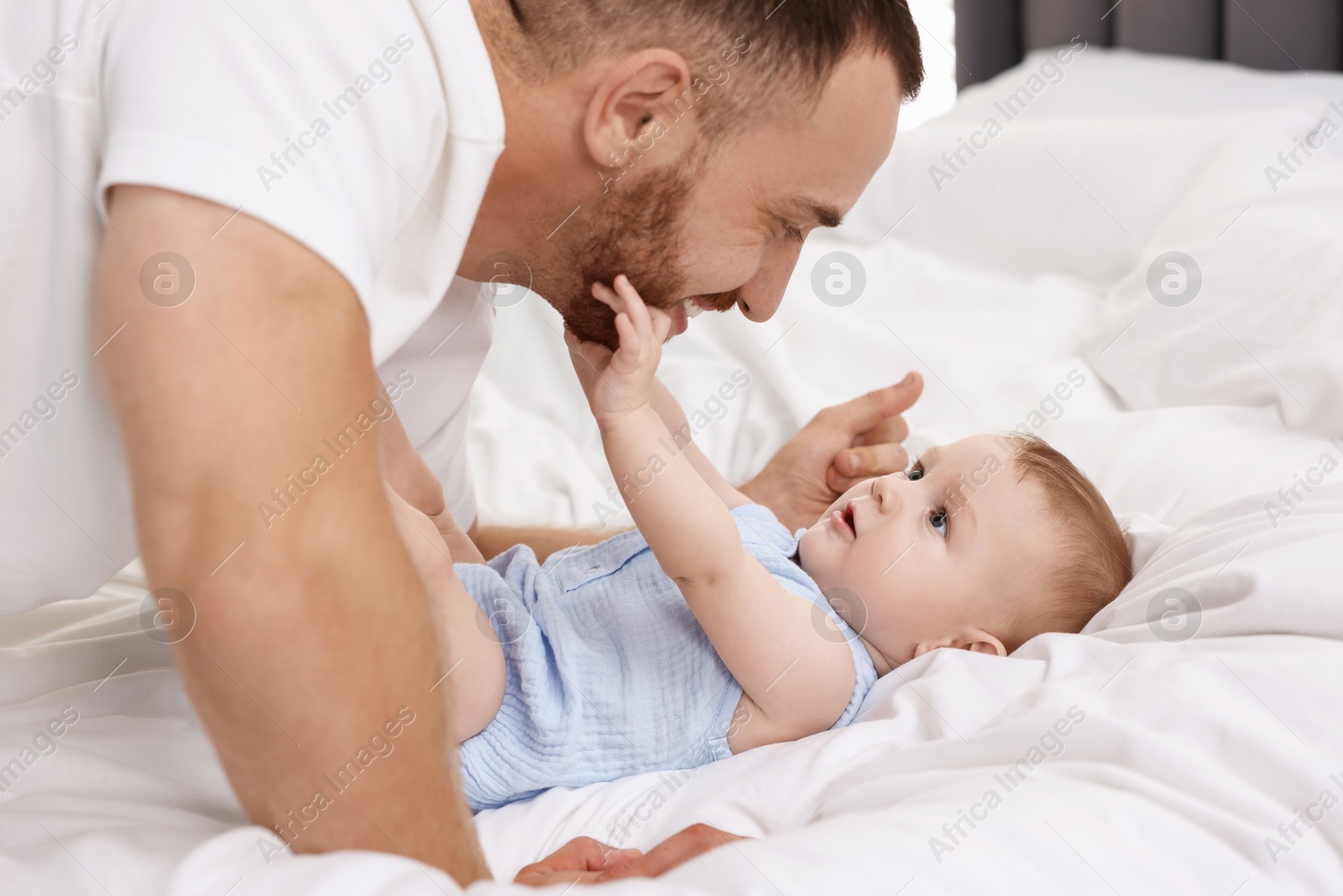 Photo of Father with his cute baby on bed at home