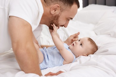 Photo of Father with his cute baby on bed at home