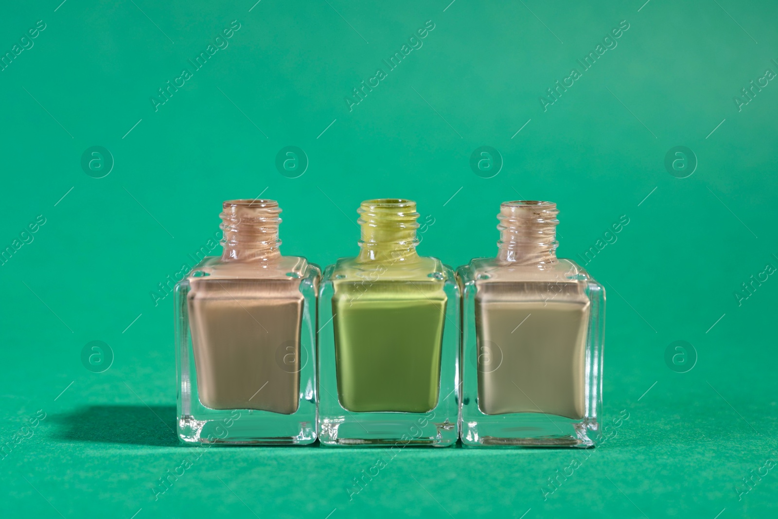 Photo of Nail polishes in bottles on green background