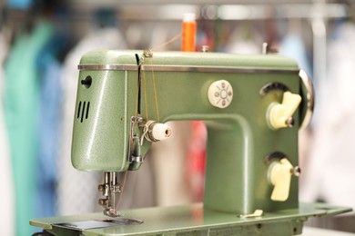 Photo of Vintage sewing machine with thread in workshop, closeup