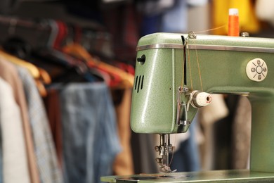 Photo of Vintage sewing machine with thread in workshop, closeup. Space for text