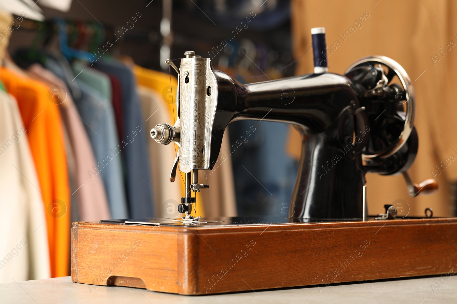 Photo of Vintage sewing machine with thread on white table in workshop