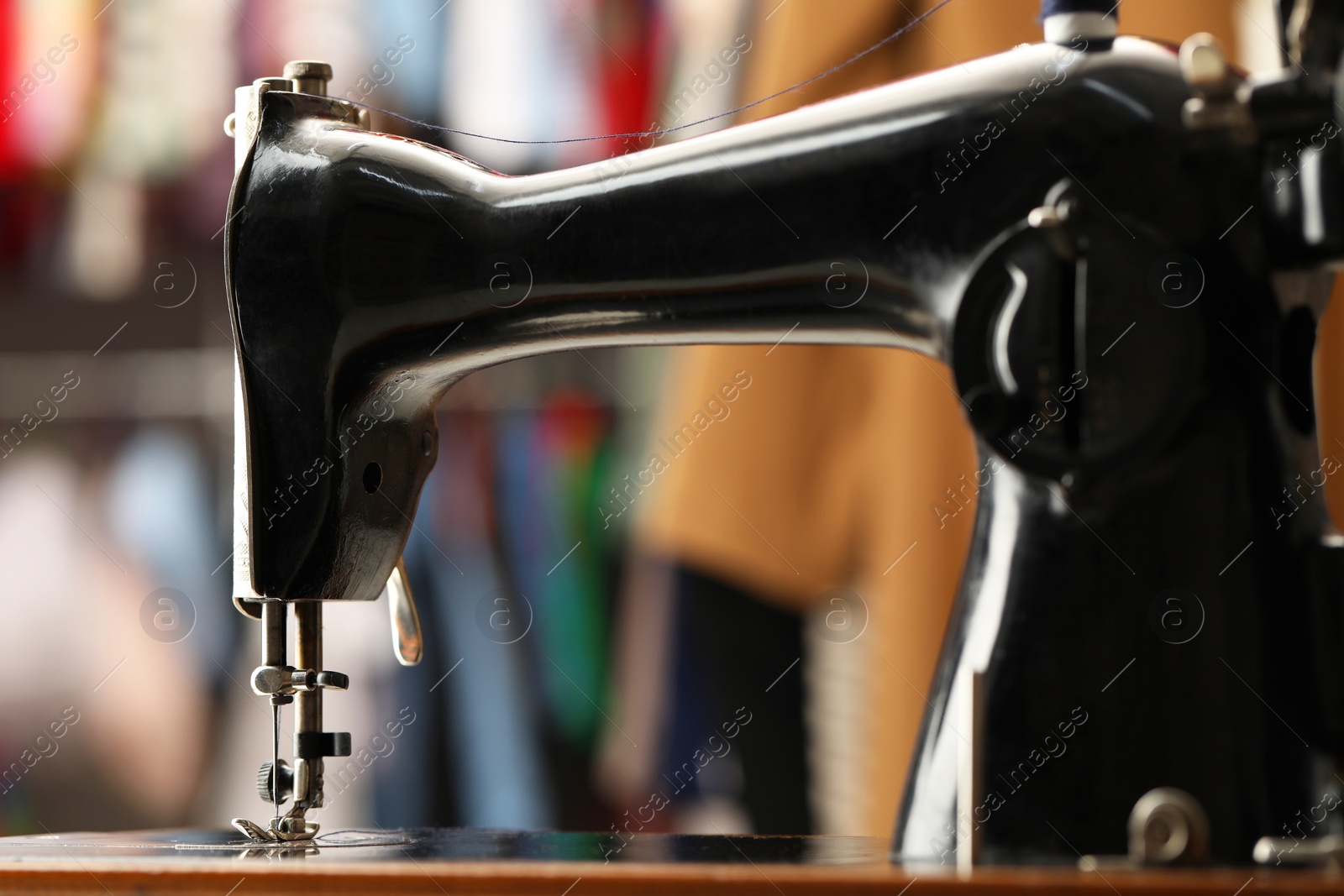 Photo of Vintage sewing machine with thread on blurred background, closeup