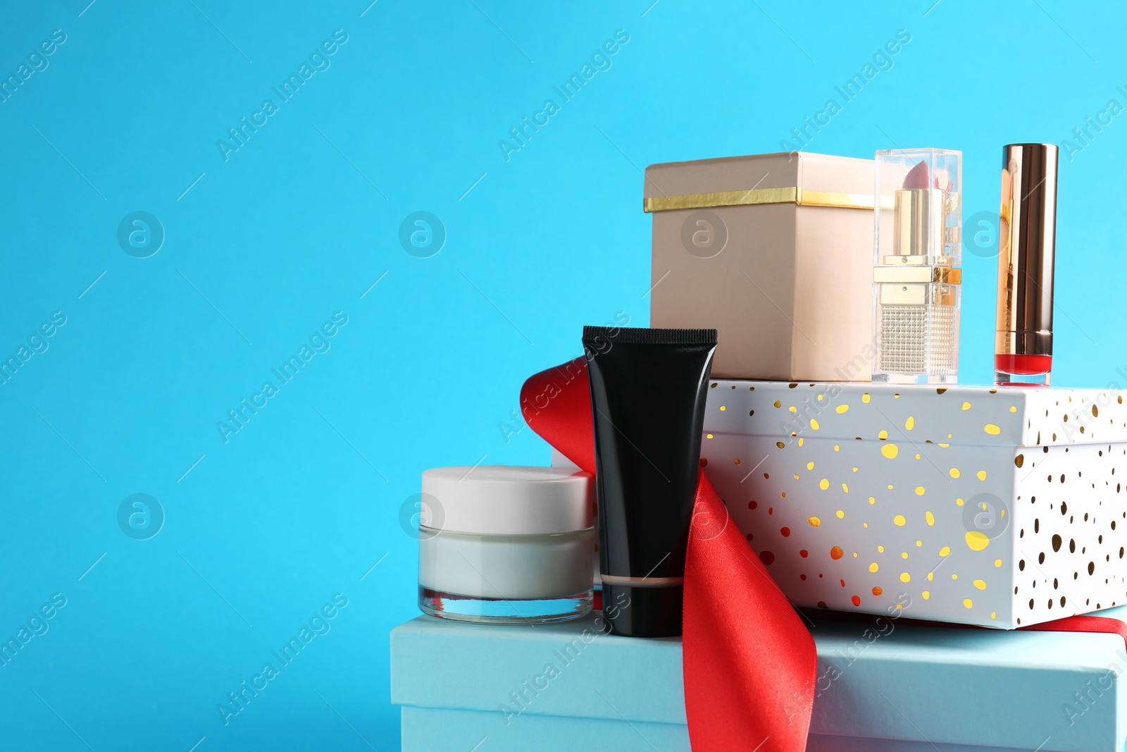 Photo of Christmas present. Decorative cosmetics and gift boxes on light blue background. Space for text