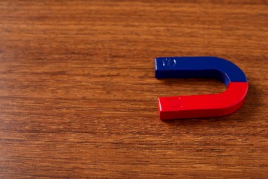 Photo of One horseshoe magnet on wooden table, space for text