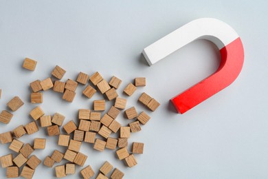 Magnet attracting wooden cubes on light grey background, flat lay