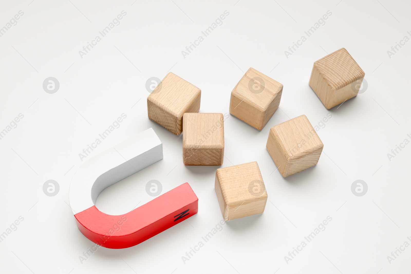 Photo of Magnet attracting wooden cubes on white background