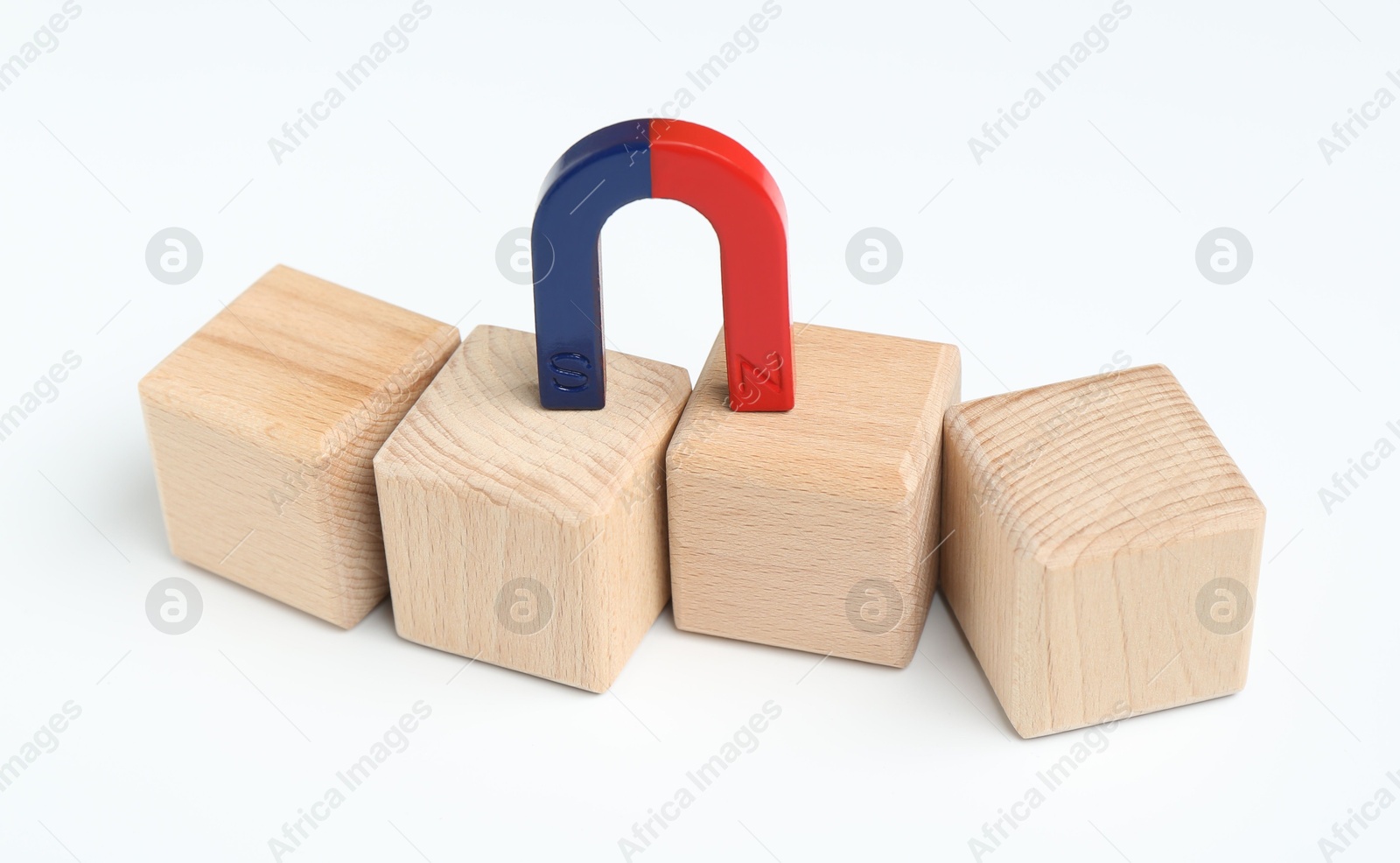 Photo of Magnet attracting wooden cubes on white background, closeup