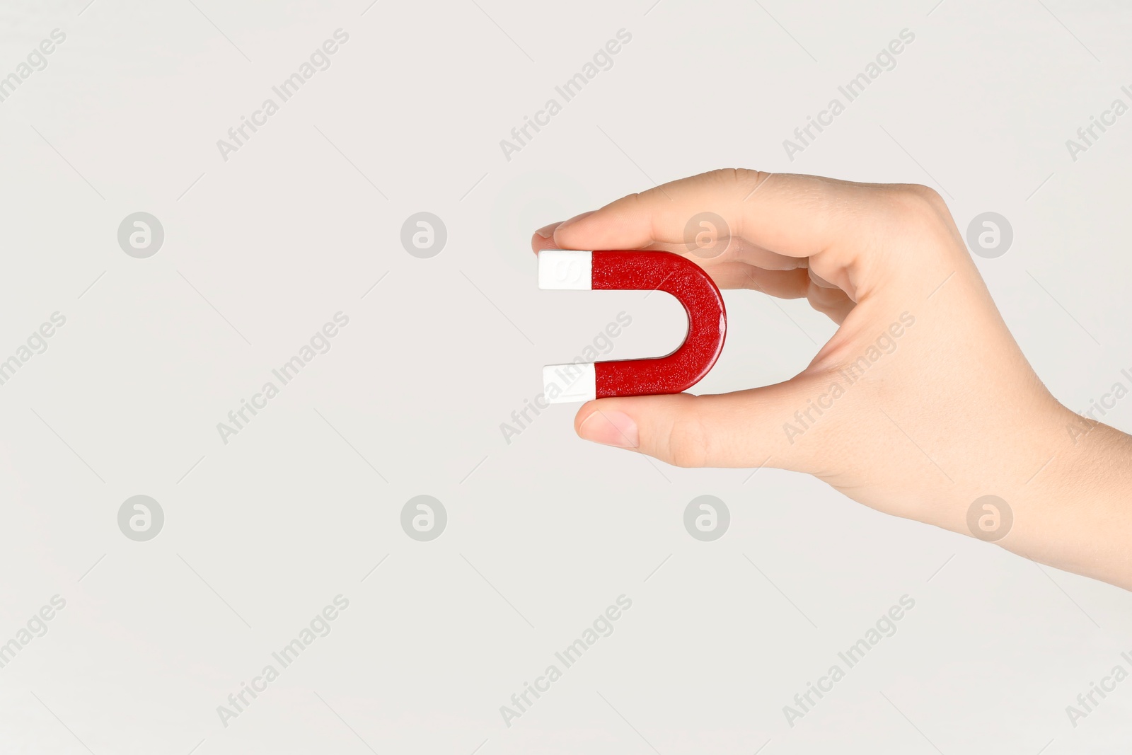 Photo of Woman with horseshoe magnet on light background, closeup. Space for text