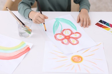 Photo of Little boy drawing at white table indoors, closeup