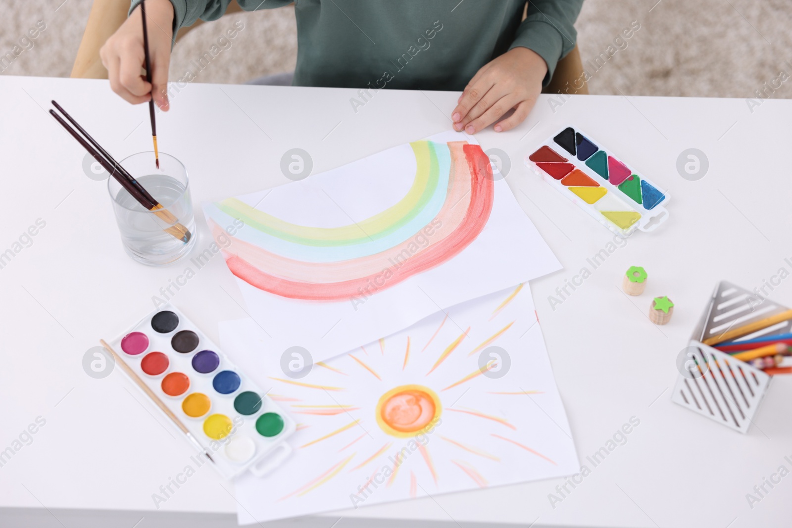 Photo of Little boy drawing at white table indoors, closeup