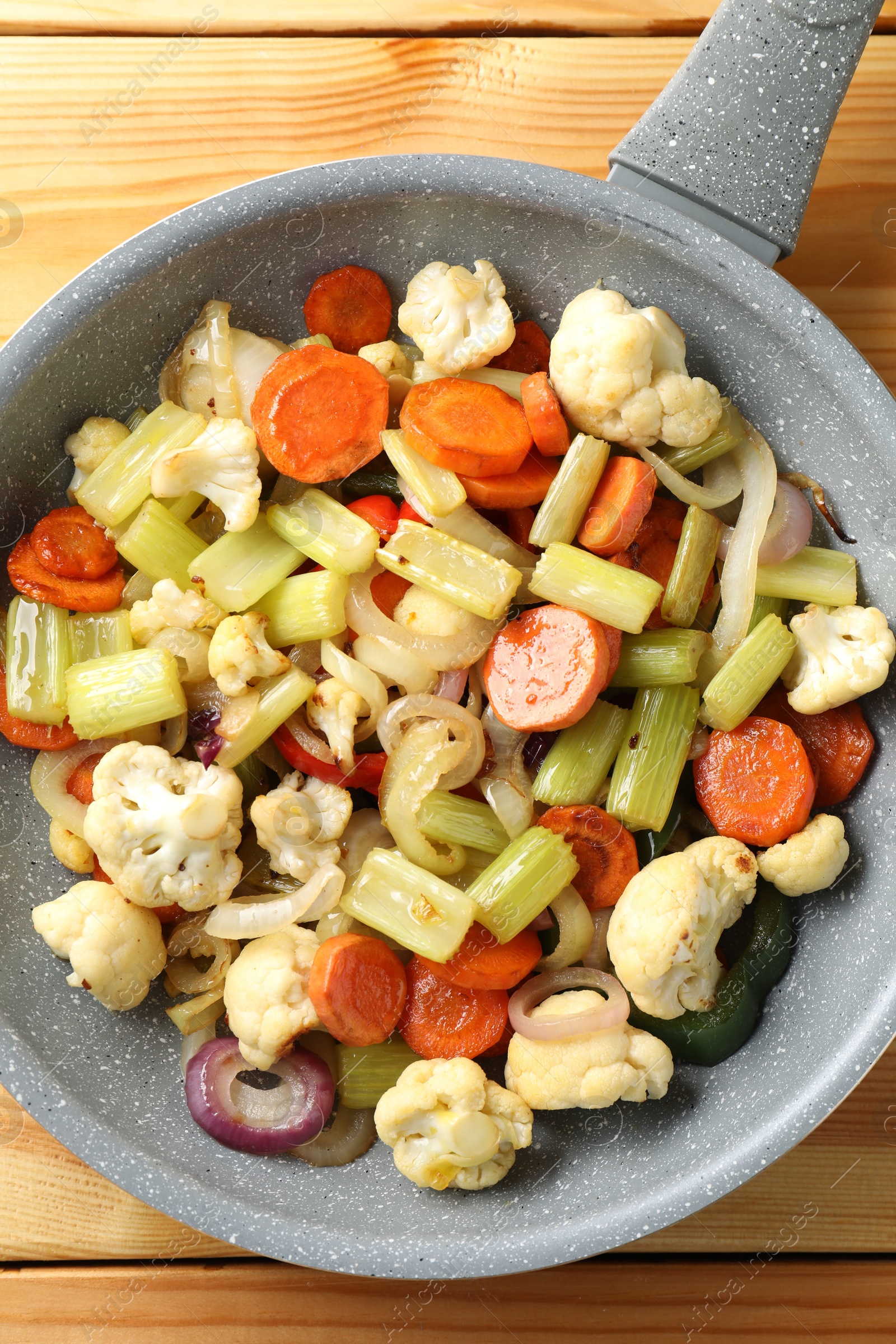 Photo of Frying pan with vegetables on wooden table, top view