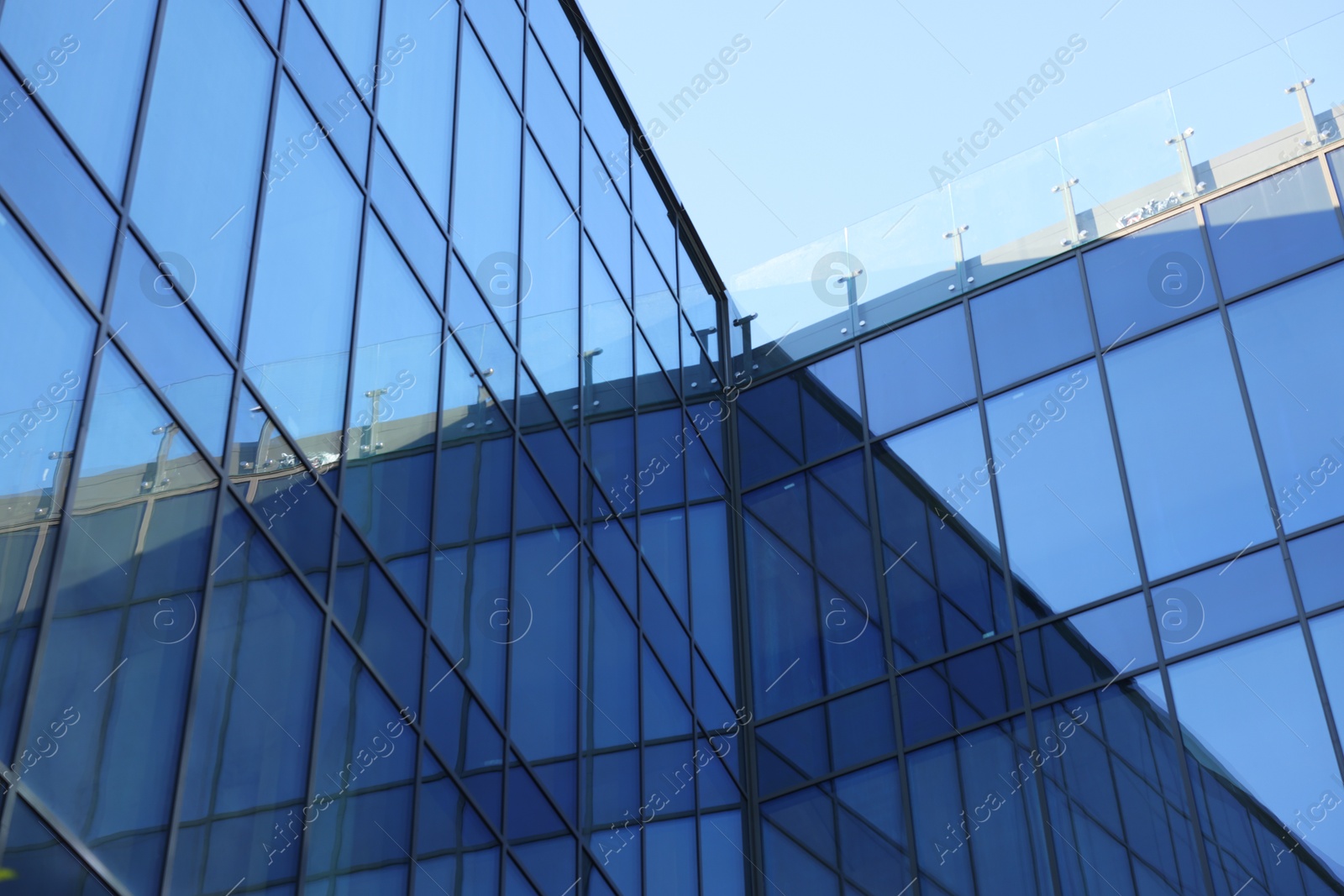 Photo of Exterior of modern building with many windows against light blue sky, low angle view