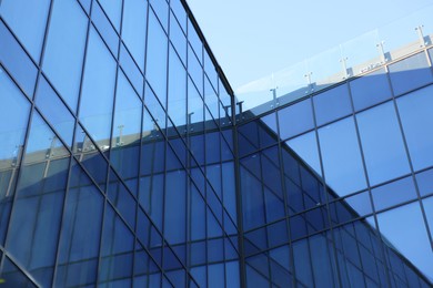 Exterior of modern building with many windows against light blue sky, low angle view