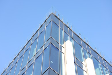 Photo of Exterior of modern building with many windows against light blue sky, low angle view