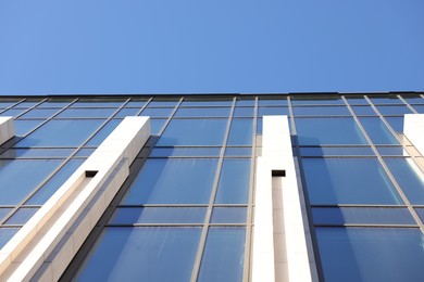 Photo of Exterior of modern building with many windows against light blue sky, low angle view