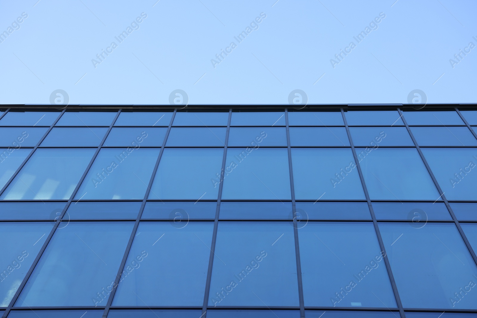 Photo of Exterior of modern building with many windows against light blue sky, low angle view