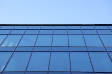 Photo of Exterior of modern building with many windows against light blue sky, low angle view