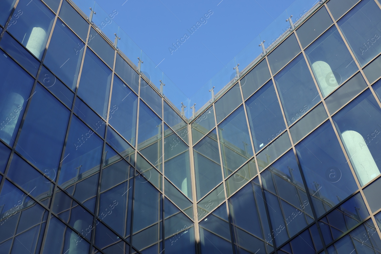 Photo of Exterior of modern building with many windows against light blue sky, low angle view