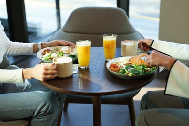 Photo of Women having tasty breakfast in cafe, closeup