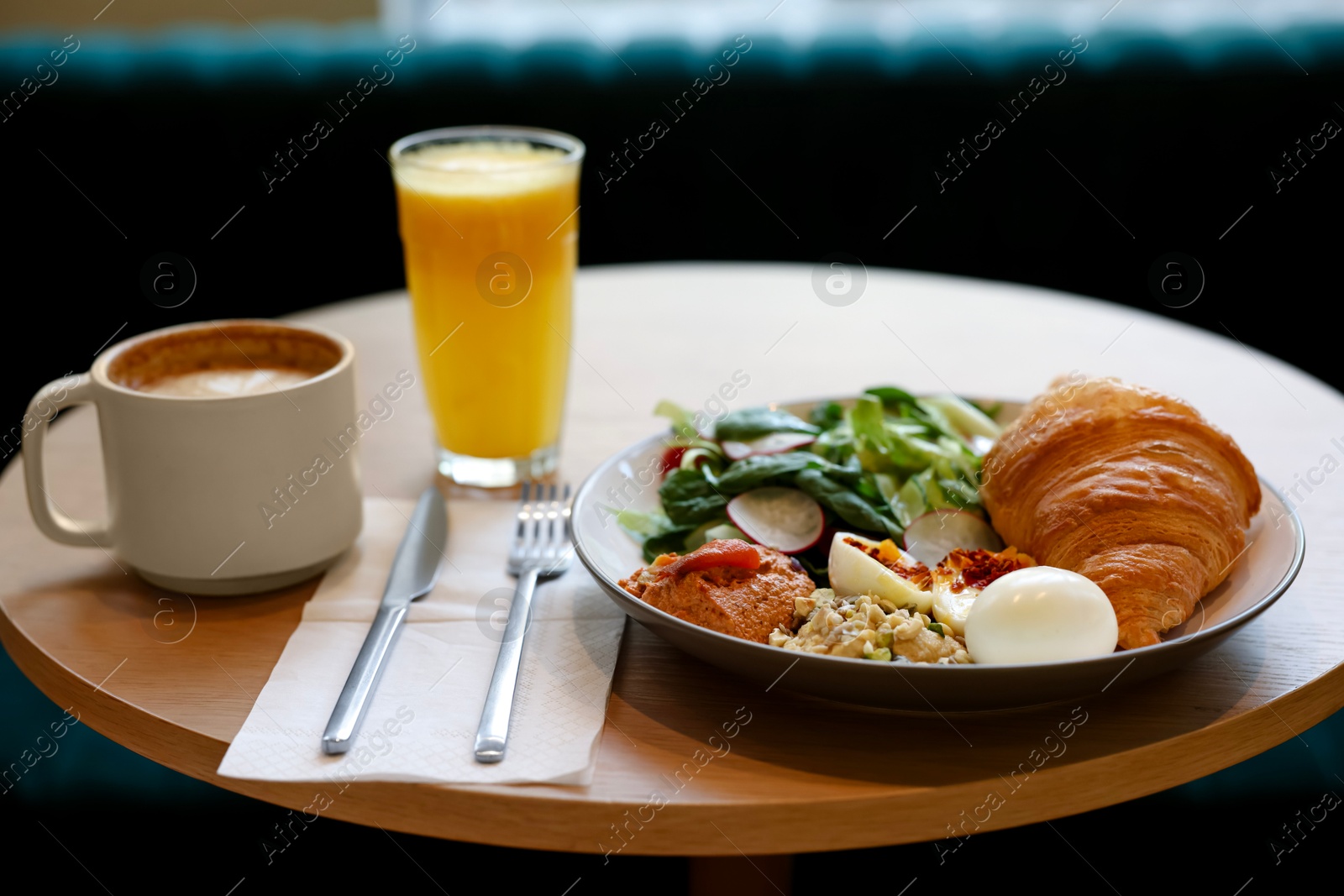 Photo of Tasty breakfast. Freshly baked croissant and salad served on wooden table in cafe