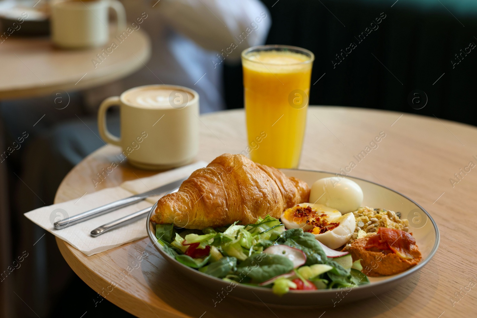 Photo of Tasty breakfast. Freshly baked croissant and salad served on wooden table in cafe, closeup