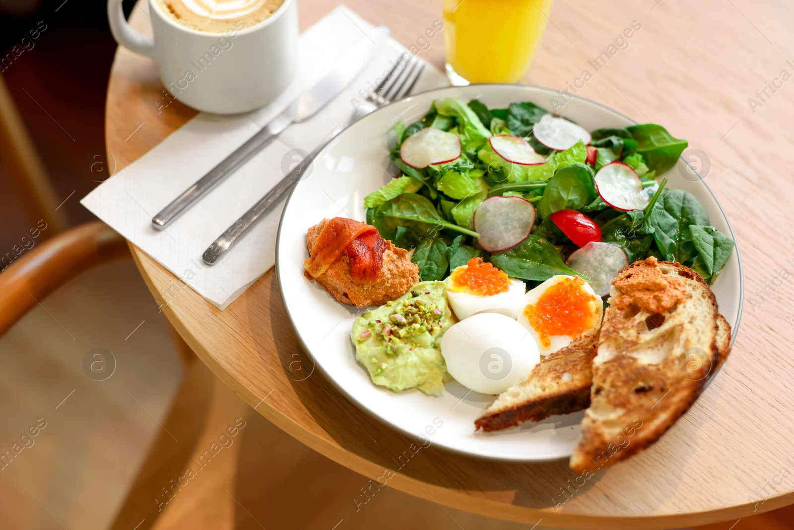 Photo of Tasty breakfast. Salad and eggs with red caviar served on wooden table in cafe, closeup