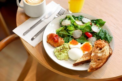 Photo of Tasty breakfast. Salad and eggs with red caviar served on wooden table in cafe, closeup