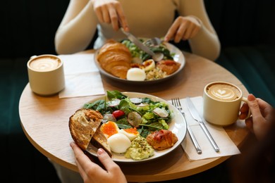 Photo of Women having tasty breakfast in cafe, closeup