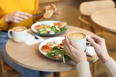 Photo of Women having tasty breakfast in cafe, closeup