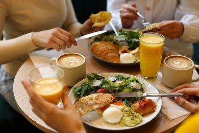 Photo of Women having tasty breakfast in cafe, closeup