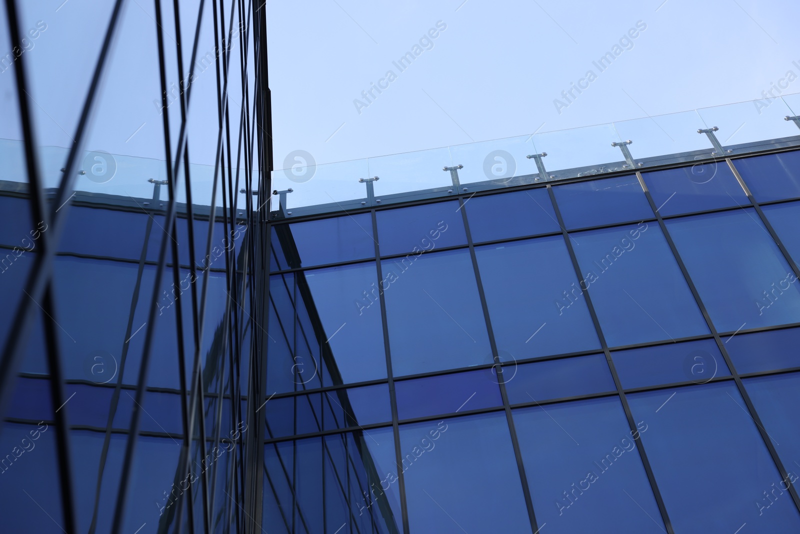 Photo of Exterior of modern building with many windows against light blue sky, low angle view