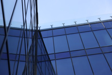 Photo of Exterior of modern building with many windows against light blue sky, low angle view