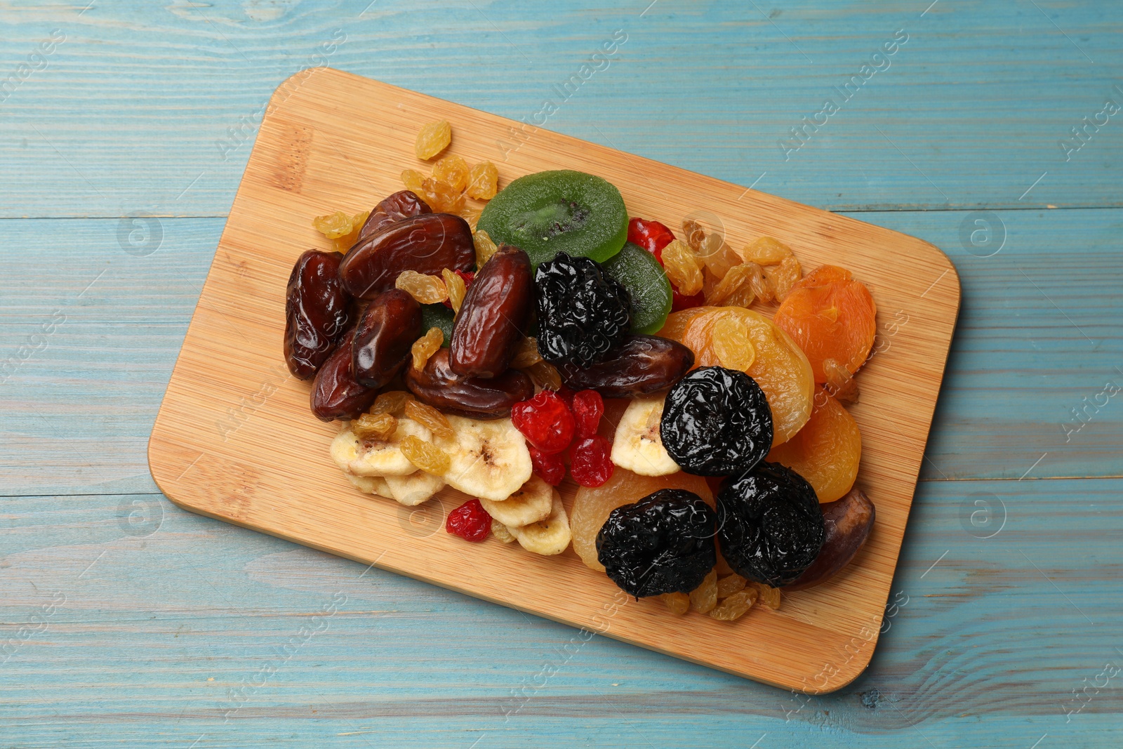 Photo of Mix of different dried fruits on blue wooden table, top view