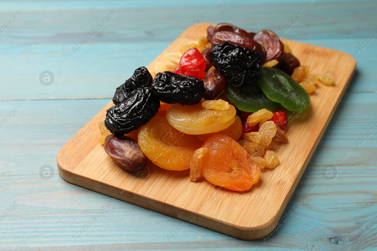 Photo of Mix of different dried fruits on blue wooden table, closeup