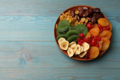 Photo of Mix of different dried fruits in bowl on blue wooden table, top view. Space for text