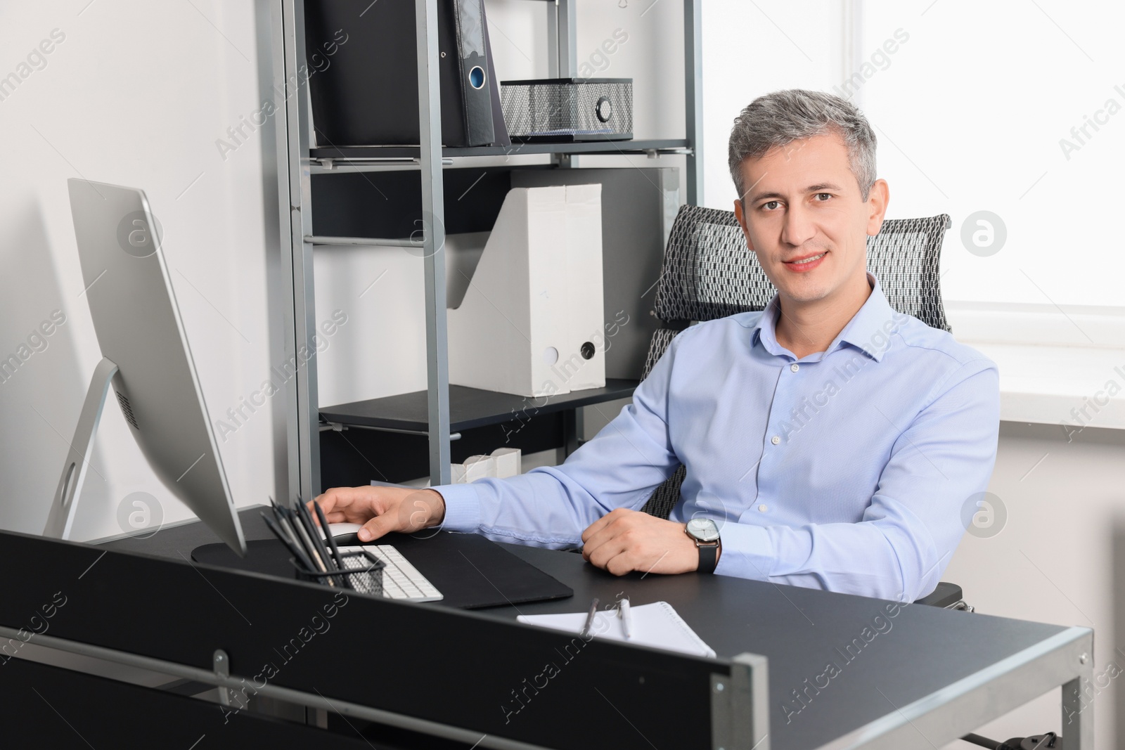 Photo of Portrait of smiling middle aged man at table in office