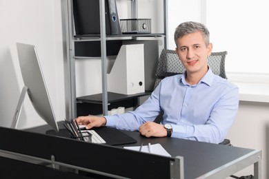 Portrait of smiling middle aged man at table in office