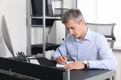 Photo of Middle aged man working at table in office