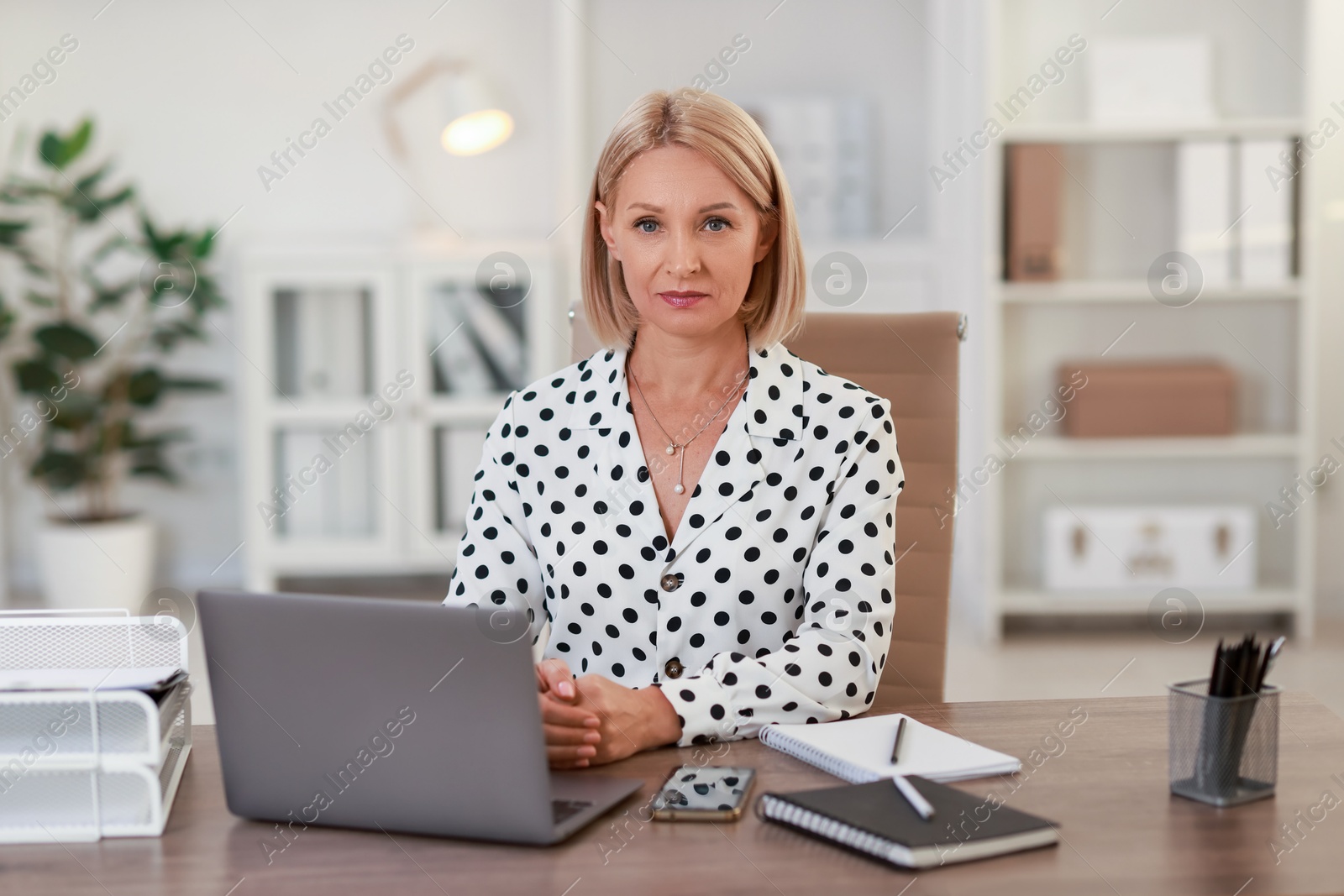 Photo of Portrait of middle aged woman at table in office