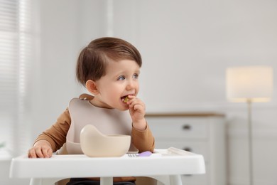 Photo of Cute little baby eating healthy food from bowl in high chair at home, space for text