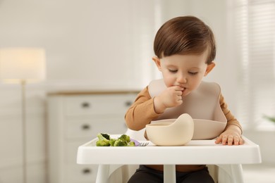 Photo of Cute little baby eating healthy food from bowl in high chair at home, space for text