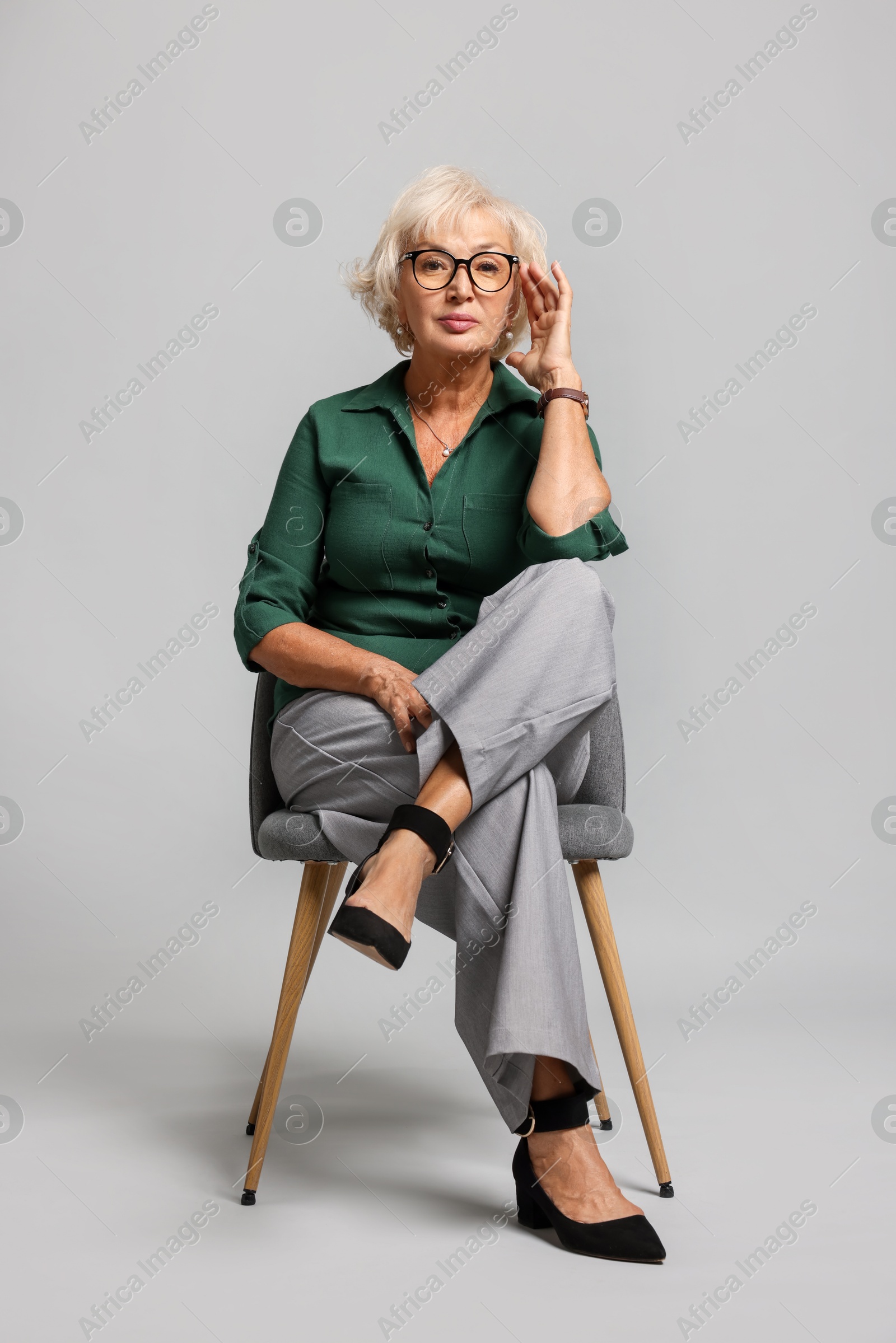 Photo of Beautiful senior woman sitting on chair against light grey background