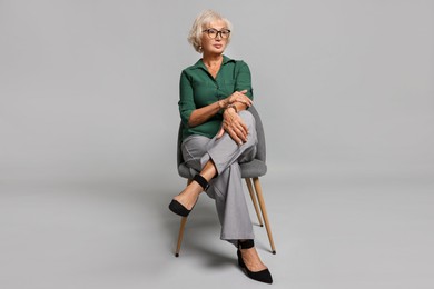 Photo of Beautiful senior woman sitting on chair against light grey background