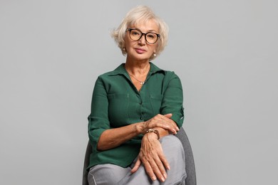 Photo of Beautiful senior woman sitting on chair against light grey background