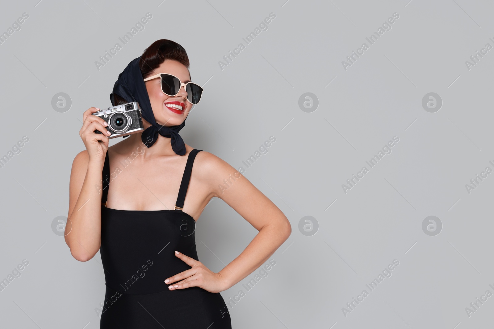 Photo of Pin-up woman in sunglasses with camera on grey background, space for text