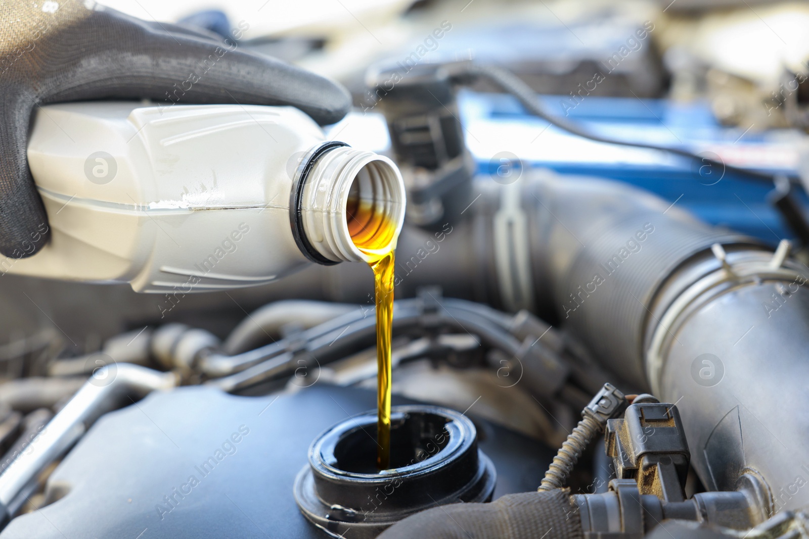 Photo of Man pouring motor oil into car engine, closeup